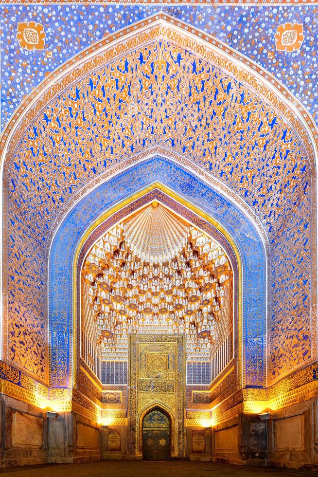 Ornate interior of a mosque with intricate tile work and chandelier
