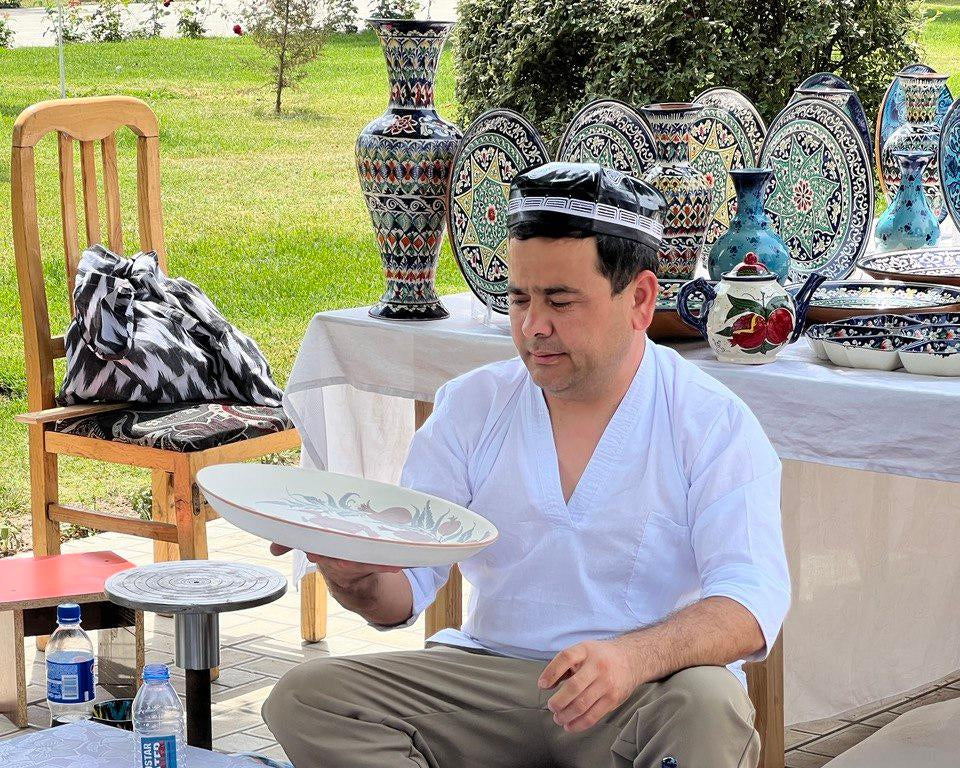Man sitting at a table with decorative ceramic items outdoors