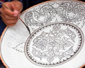 Master Usta painting the plate with a brush